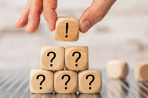 Die häuftigsten Fragen zu Refluctan. Eine Person legt Würfel mit Fragezeichen zu einer Pyramide.