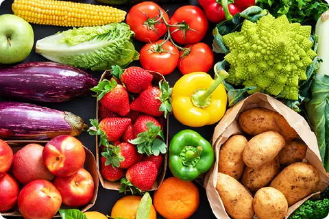 Une table pleine de légumes et de fruits colorés comme des fraises, des aubergines, des pommes de terre, des poivrons