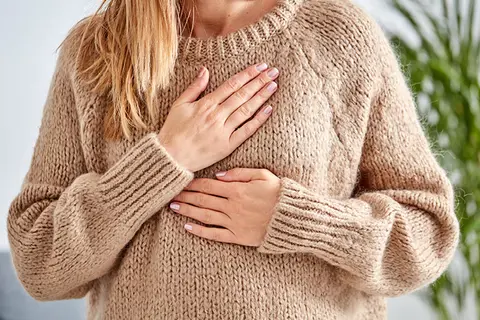 Frau hält sich Hände an die Brust wegen Reflux