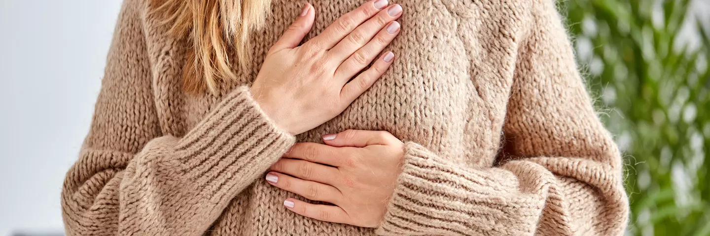 Frau hält sich Hände an die Brust wegen Reflux