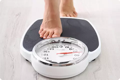 Quelqu'un se met sur une balance - Un poids sain aide à lutter contre les brûlures d'estomac