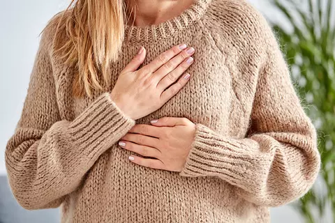 Was ist Reflux? Frau hält sich beide Hände an die Brust.