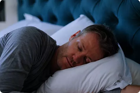 Mann schläft im Bett - Reflux in der Nacht