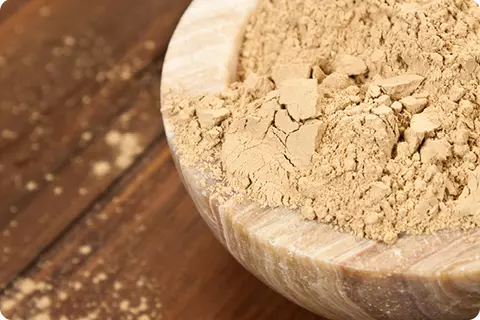 Holzschale mit Heilerde auf einem Holztisch - Reflux mit Hausmittel behandeln