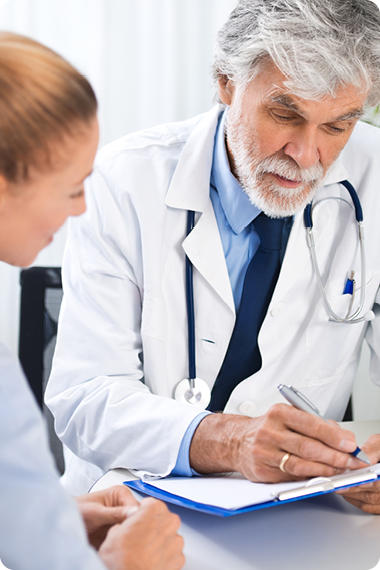 Arzt mit Notizblatt sitzt neben Patientin - wann sollte man mit Reflux zum Arzt