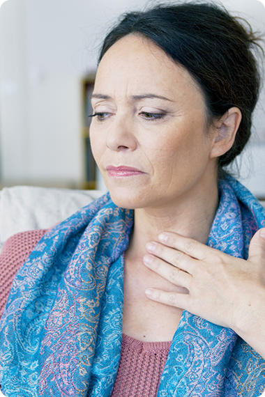 Une femme âgée porte la main à son larynx - Quel est le point commun entre les muscles et les brûlures d'estomac ?