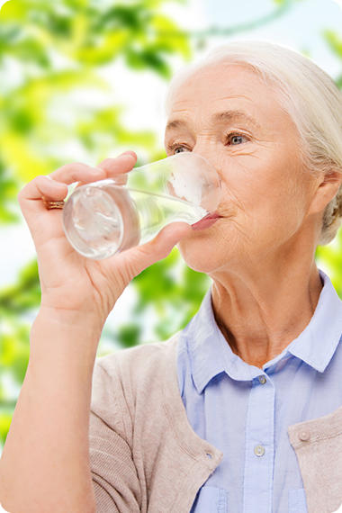 Une femme âgée boit un verre d'eau - brûlures d'estomac dues à une faible salivation
