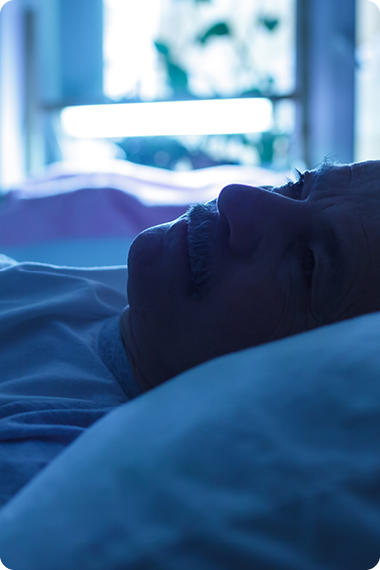 Mann liegt wach im Bett - Warum ist Magenbrennen nachts schlimmer?