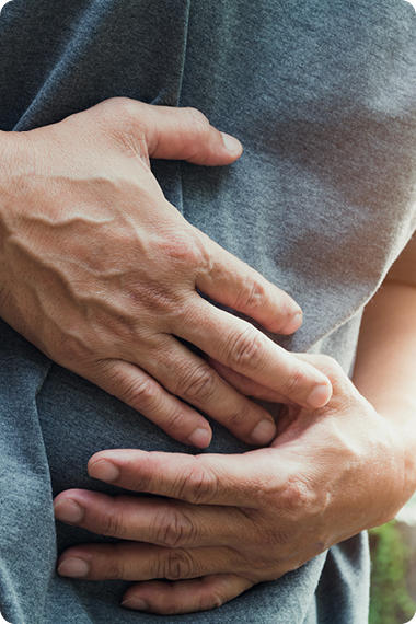 Mann hält sich beide Hände an den Bauch - Stress kann Durchfall und Verstopfung beschleunigen