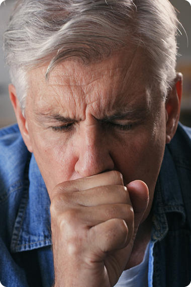 Mann mit grauen Haaren muss husten - Stiller Reflux löst viele Beschwerden aus