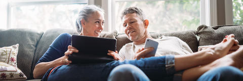 Zwei Personen sitzen lachend auf dem Sofa und schauen auf ein Tablett - Service Refluctan, Tipps, Broschüren, Glossar